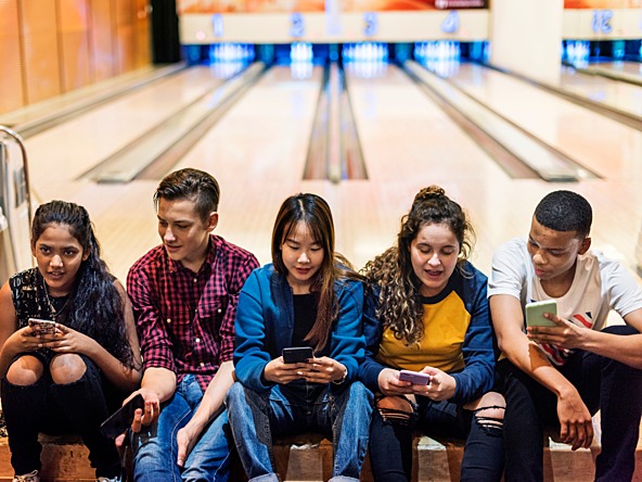 Teenagers on phones at bowling alley